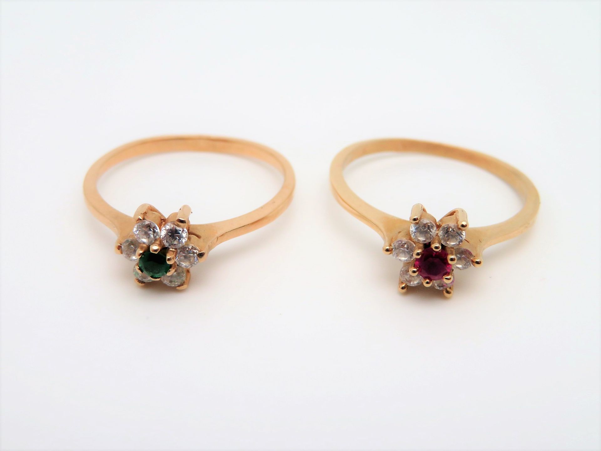 2 Ringe, wohl Russland, Blütenform, besetzt mit grünem sowie rubinrotem, facettiertem Stein, umgebe