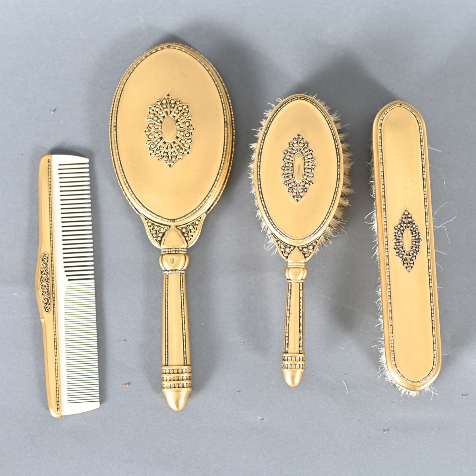 Frisiertoiletten-Garnitur, vier Teile, um 1920, Metall vergoldet, Perlenbandverzierung, Spiegel