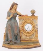 Uhrenweibchen, 19. Jh., Holz, farbig gefasst: junge Frau neben einem Uhrengehäuse sitzend, in dem si