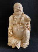 China, ca. 1920, Buddha, Elfenbein. Der sitzende Buddha trägt über dem dicken Bauch eine zweireihige
