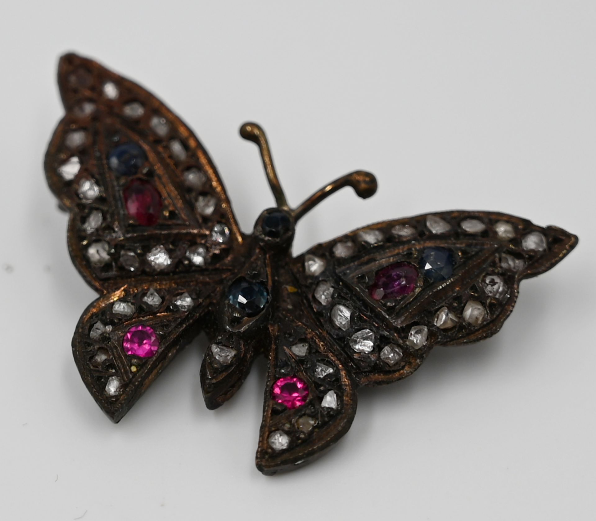 1 Brosche "Schmetterling" mit Diamantsplittern wohl Rubine, wohl Saphire, wohl GG 8ct. Asp.