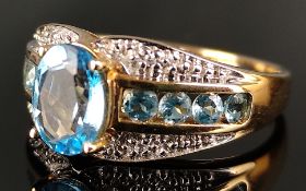 Ring mit ovalem Schmuckstein, blau und facettiert, daneben je eine Reihe hellblauer Steine, und vier