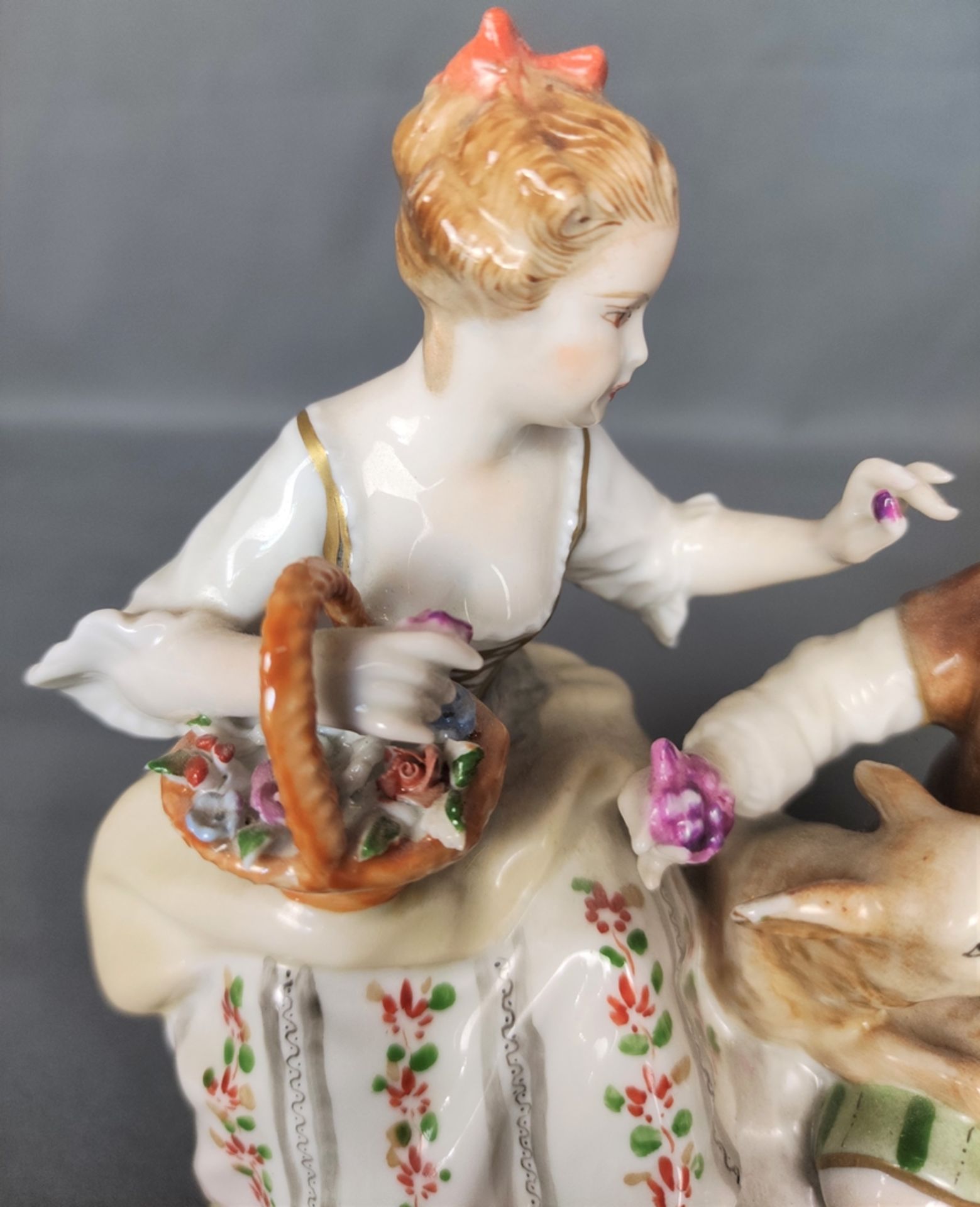 Porcelain group, couple sitting, between them a little sheep, her holding a flower basket, handing  - Image 2 of 3