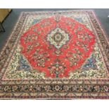 A large hand woven Hamadan carpet, central oval lozenge, surrounded by a festooned floral red and