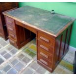 A 1930 oak pedestal desk, central arched door, four drawers to pedestals, leather writing surface,