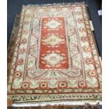 A Turkish hand woven woollen rug, central panel of three diamond lozenge medallions, surrounded by