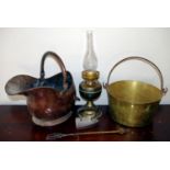 A brass jam pan; a copper helmet shaped coal scuttle; a brass oil lamp; flat iron (4)