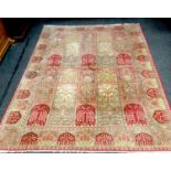 A handwoven Indian silk rug, decorative panels in hues of sage, cream, and cardinal red. 328cm x