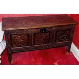An 18th century oak blanket box, the front and top carved with floral panels and lunettes, tall feet