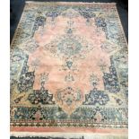 A large rug, floral designs in cerulean blue and cafe-au-lait on a salmon and cobalt ground. 358cm x