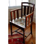 An Arts and Crafts elbow chair, slat back and arms, rush seat, turned legs, H stretcher