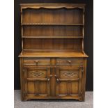 A 20th century oak dresser, outswept cornice above plate racks, the slightly projecting base with
