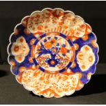 A Japanese Imari shaped circular charger, the central field painted with a vase of flowers, trails