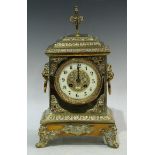 A brass mantel clock, ivorine chapter ring, Arabic numerals, twin winding holes, pair of lion mask