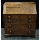 A George III oak bureau, fall front enclosing an arrangement of pigeonholes and small drawers, above