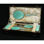 A George V Art Deco silver and green enamel backed six piece dressing table set, cased, Birmingham
