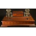 An Irish Arts and Crafts mahogany desk top inkstand, the central rectangular box flanked by a pair