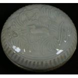 A Chinese celadon circular box and cover, moulded in relief with a duck amongst lotus, 8cm diam