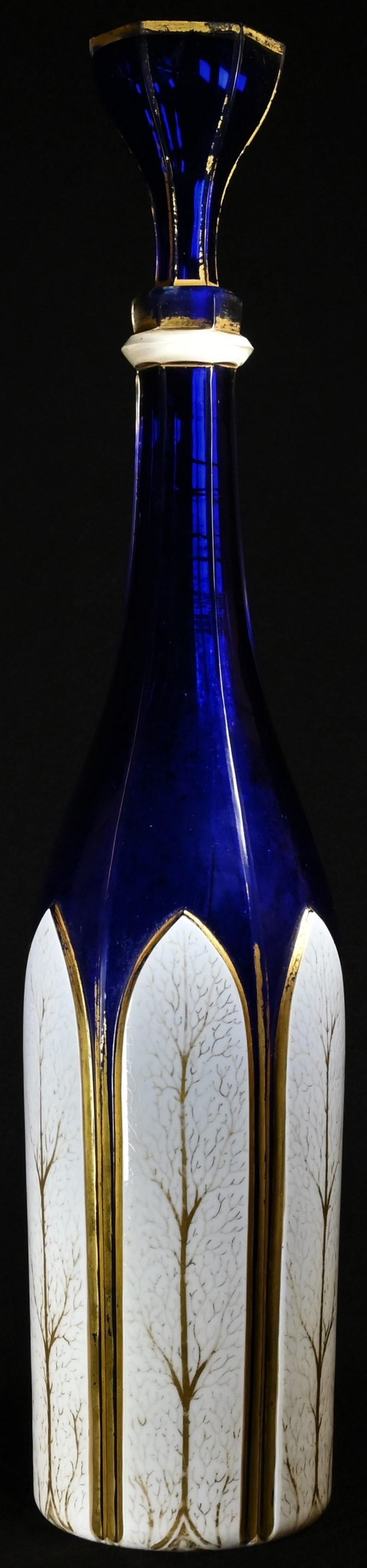 A 19th century Bohemian white overlaid blue glass slender facetted mallet shaped decanter, the lower