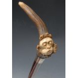 An early 20th century silver-mounted novelty walking stick, the stag antler handle carved with the