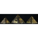 A set of three graduated pyramid desk models, each decorated in gilt with Egyptian devices, on a