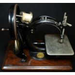 A 19th century American C-frame sewing machine, by Willcox & Gibbs, New York, wooden base, 33cm