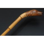 An early 20th century novelty walking stick, the pommel carved as the head of a dog, bamboo cane,