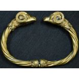 A Grecian Revival gilt metal hinged bangle, terminating in rams' head masks, 8.5cm wide