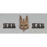 A WWII SAS cap badge and shoulder titles, theatre made sand cast, most likely made in Cairo