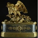 A French Empire gilt and dark patinated bronze chenet, crested by an eagle, 28cm wide, 19th century