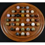 A collection of polished geological specimen stones and marbles, displayed upon a turned mahogany