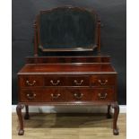 A George II style mahogany dressing table, shaped rectangular adjustable mirror above an arrangement