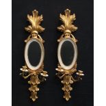 A pair of gesso type mirrored wall sconces, oval mirrors, 74cm high