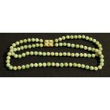 A double strand of spherical polished composite green agate beads, united by a four stone cabochon