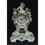 A German porcelain Rococo style mantel clock on stand, surmounted with a Bacchic bust flanked by