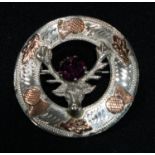 A Scottish silver and gold coloured metal brooch, as a stag's head, set with a purple stone, 4cm