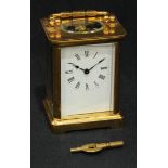 A brass carriage clock, five glass panels, white enamel dial with Roman numerals, swing handle, with