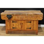 A pine workshop/work bench, each long side with a vice, the front with a pair of cupboard doors,