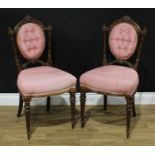 A pair of Victorian imitation rosewood boudoir chairs, each oval back crested by a scrolling