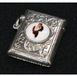 A sterling silver vesta, set with an enamel plaque depicting a lady wearing furs