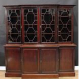 A George III style mahogany break-centre library bookcase, outswept dentil cornice above four glazed