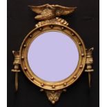 A Regency style bullseye girandole looking glass, bevelled circular mirror plate crested by an eagle