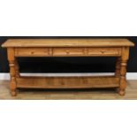 A country cottage pine serving table, oversailing rectangular top above three frieze drawers, turned