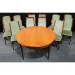 A G-Plan extending dining table and chairs, the circular table extending to discorectangle with