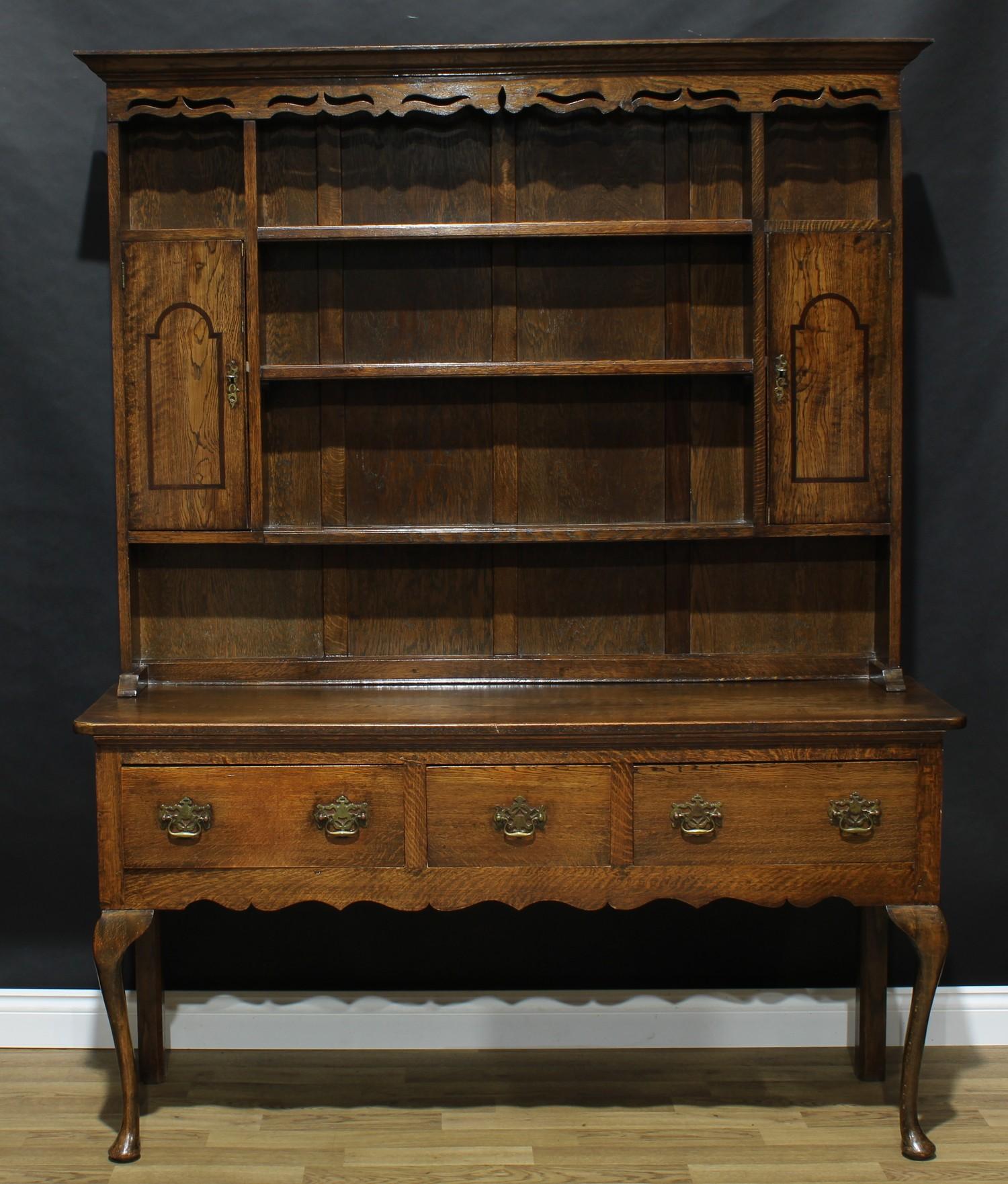 A George II style oak dresser, outswept cornice above three plate racks, a pair of open niches and