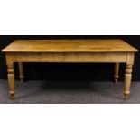 A country cottage pine dining table, rounded rectangular top above a deep frieze, turned legs,