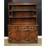 A George III style oak dresser, moulded cornice above two plate racks, two niches and a pair of