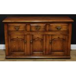 A George III style oak low dresser or sideboard, oversailing moulded rectangular top above three