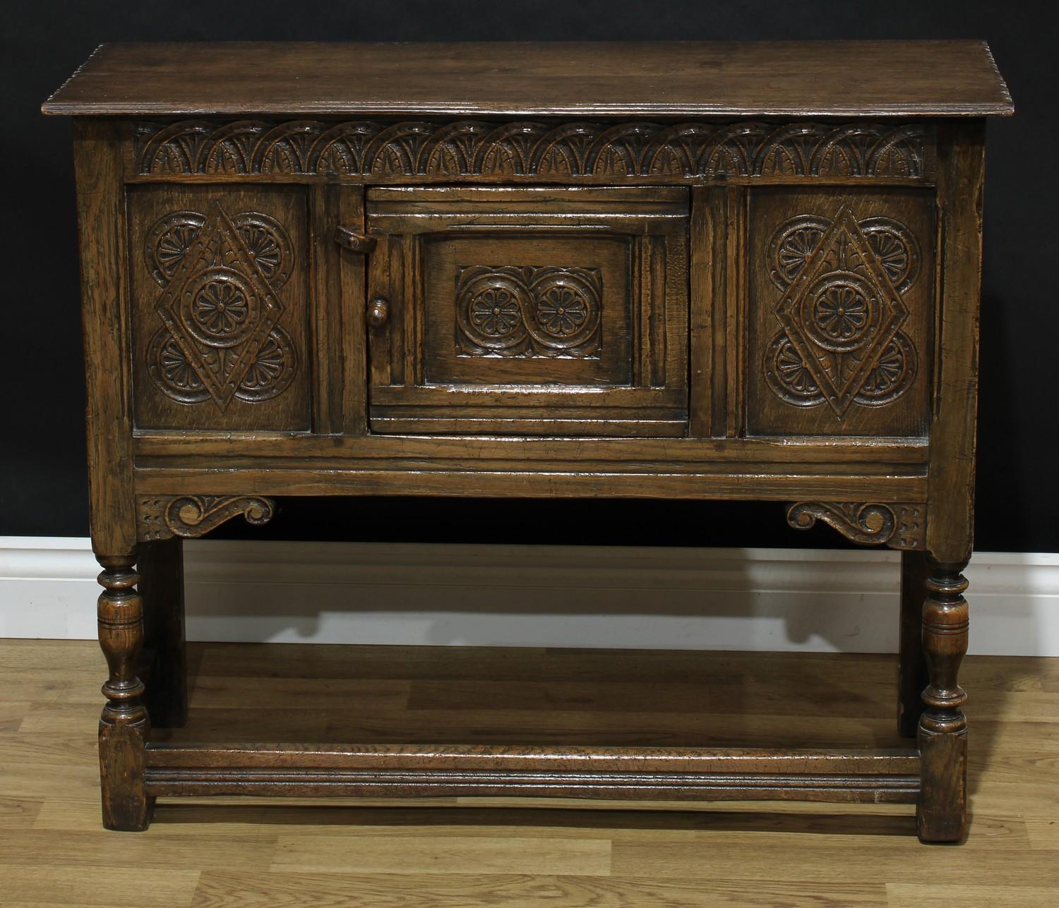 A 17th century style oak low side cabinet, oversailing rectangular top above a central panel door,