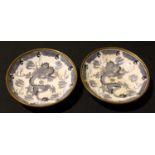 A pair of brass cased Oriental blue and white dragon dishes, 14.5cm diameter